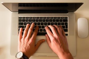 Hands typing at a laptop keyboard