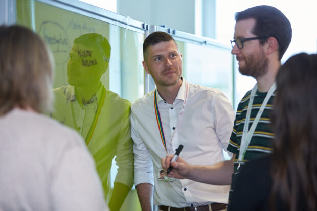 four people standing in front of a whiteboard