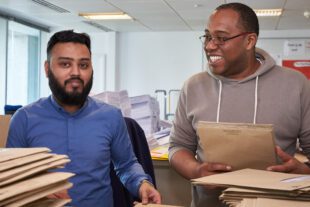 Two men with piles of brown envelopes 