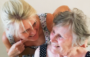 An older woman and her daughter sit laughing together