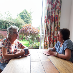 Maureen (left) and Petra (right) sat at a table with a cup of tea each